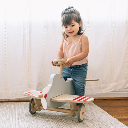 Child playing with a wooden toy airplane indoors