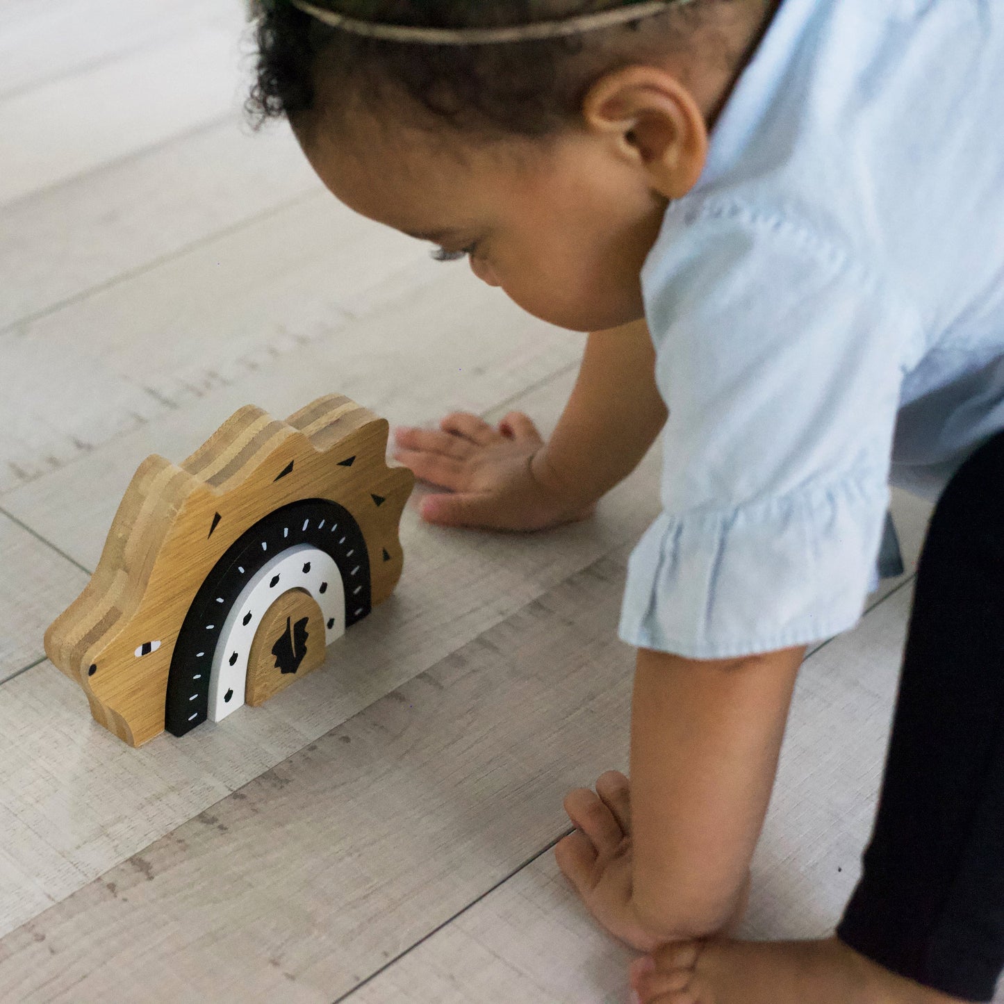 Child playing with a wooden toy on a light wooden floor