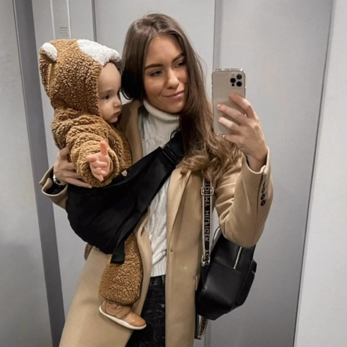 Woman taking a mirror selfie with a child in a bear costume