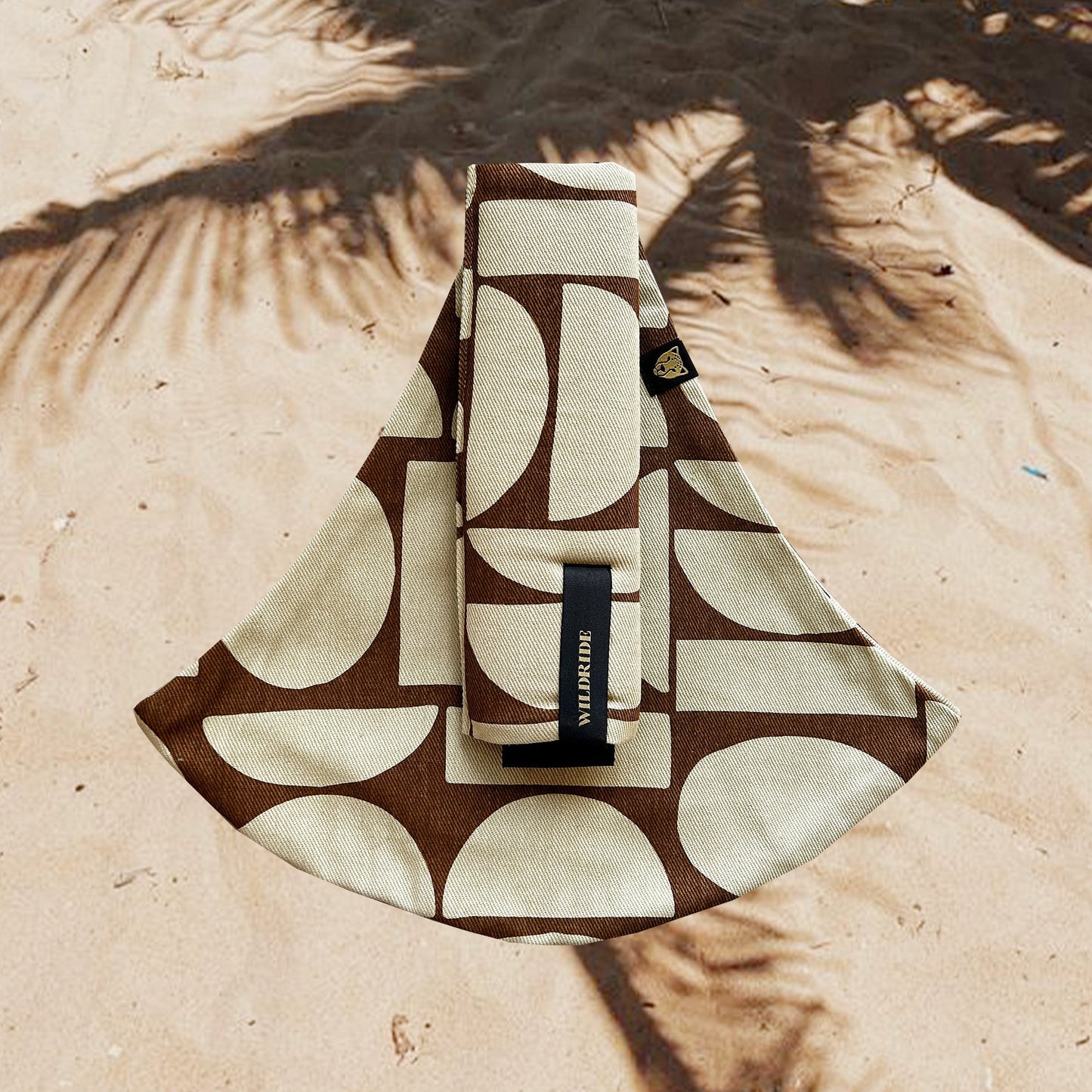 Patterned pouch with a brand label on a sandy background