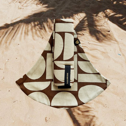 Patterned pouch with a brand label on a sandy background