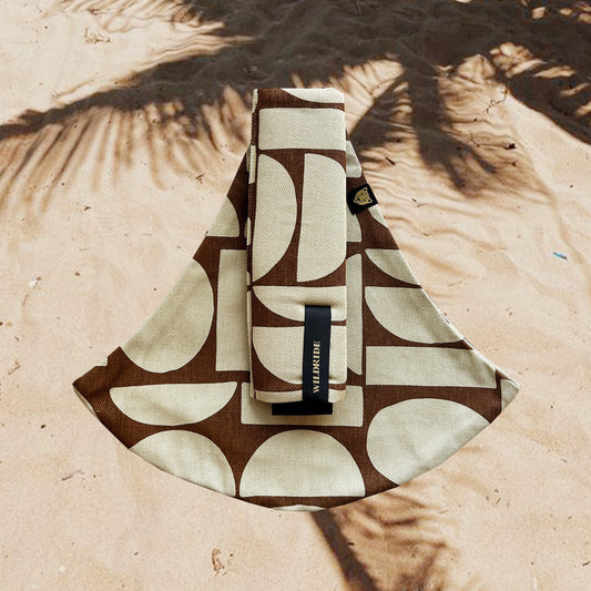 Patterned pouch with a brand label on a sandy background