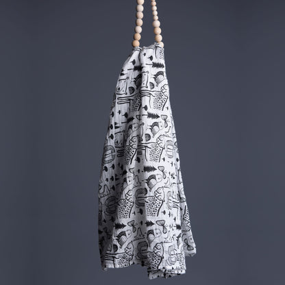 White towel with black patterns hanging from wooden beads against a gray background