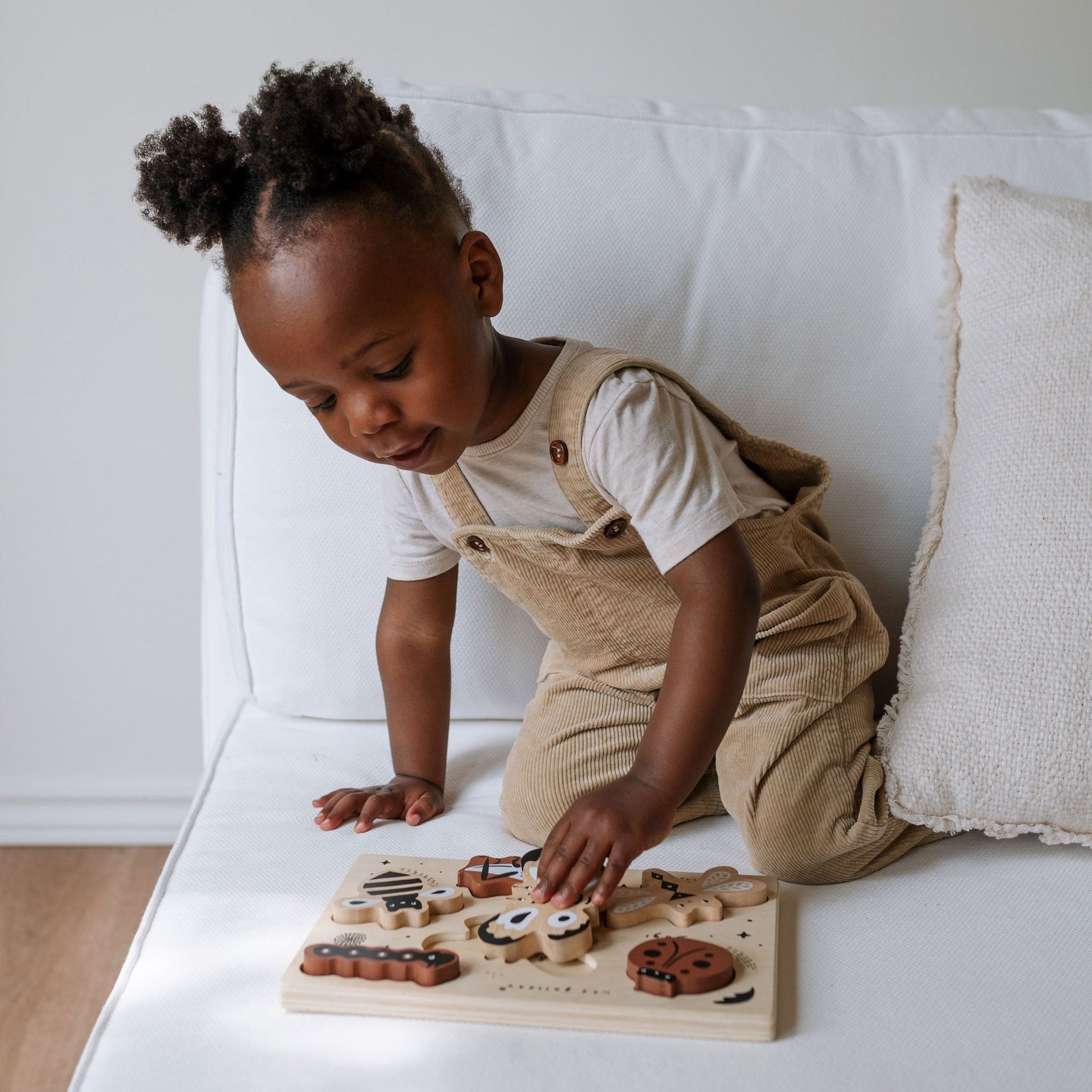 Child playing with a wooden toy on a white couch