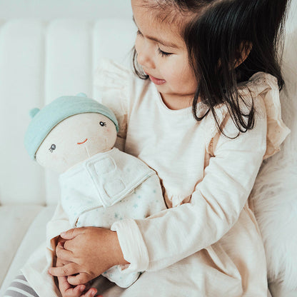 Child holding a plush toy on a soft surface