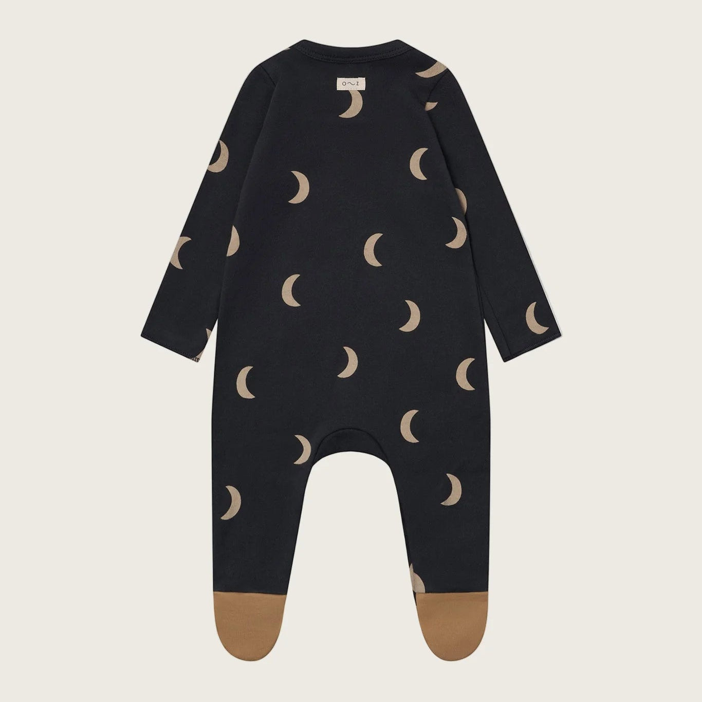 Black baby onesie with moon pattern on a beige background