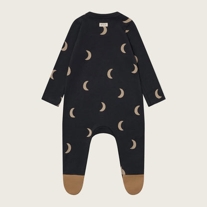 Black baby onesie with moon pattern on a beige background