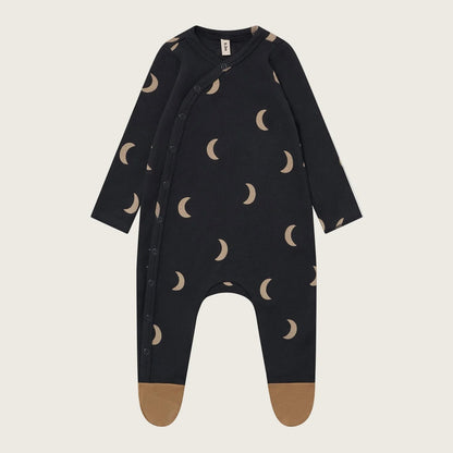 Black baby onesie with moon pattern on a beige background