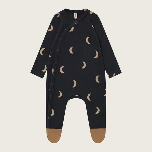 Black baby onesie with moon pattern on a beige background