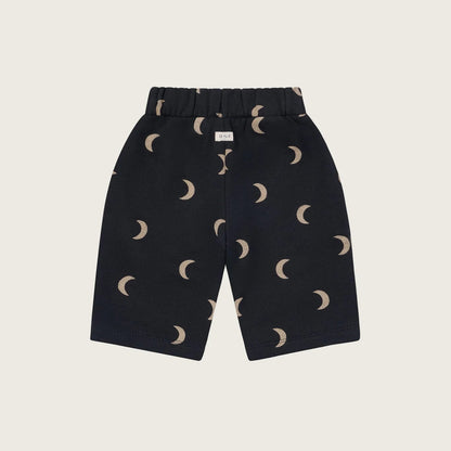 Black shorts with moon phase pattern on a beige background