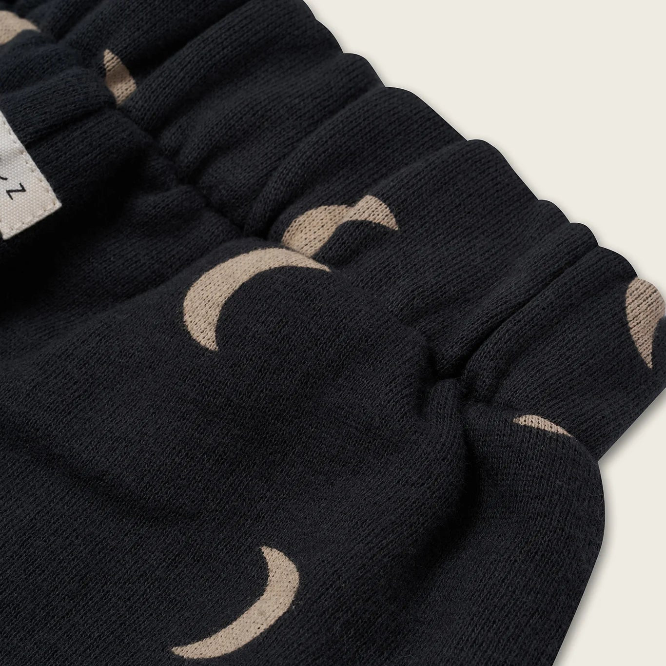 Black pants with beige moon patterns on a light background