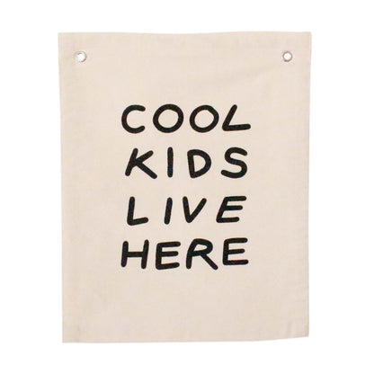 Beige canvas wall hanging with 'Cool Kids Live Here' text on a white background