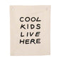 Beige canvas wall hanging with 'Cool Kids Live Here' text on a white background