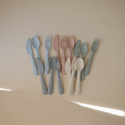Set of colorful cutlery including knives, forks, and spoons on a beige background