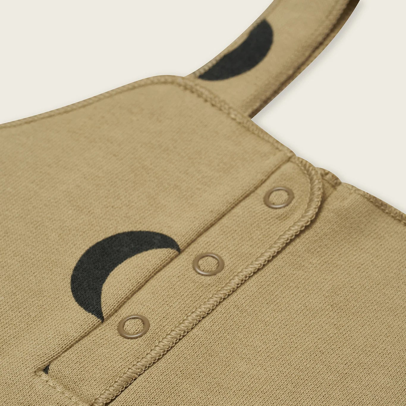 Close-up of a beige garment with black crescent moon designs on a white background