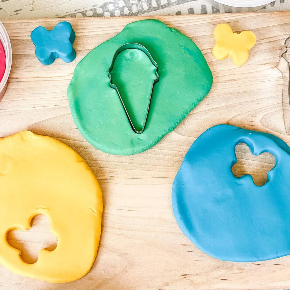 Colorful play dough with cookie cutters on a wooden surface