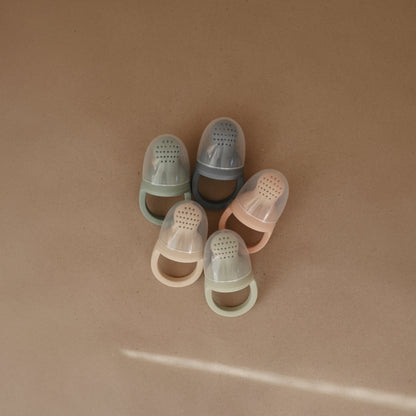 Set of five transparent baby shoes in various colors on a beige background