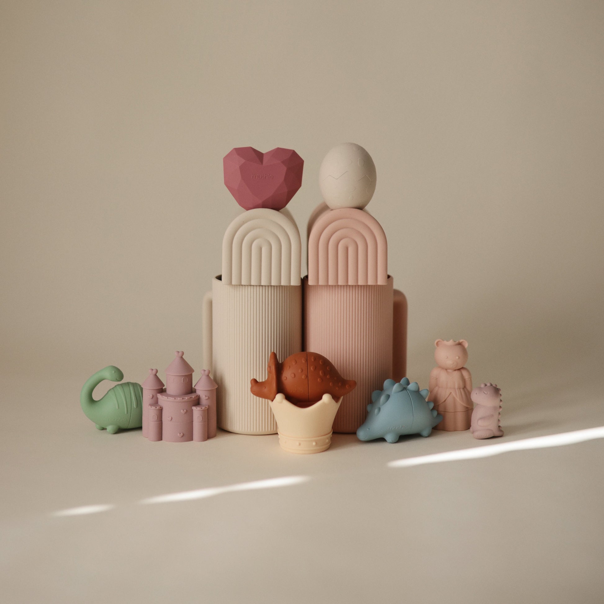 Set of pastel-colored ceramic toys on a beige surface with a neutral background