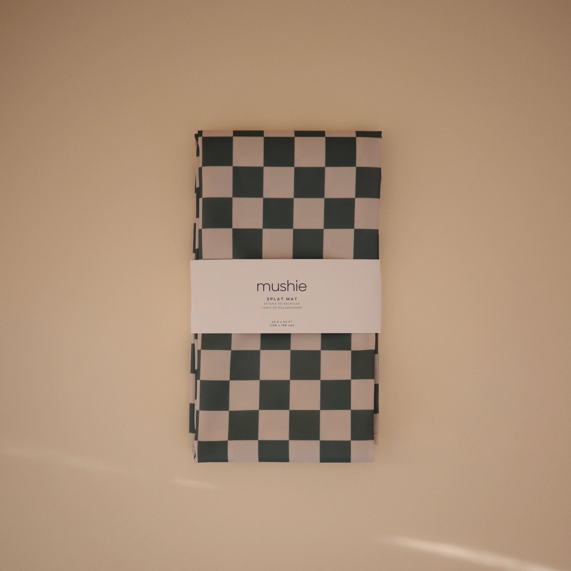 Checkered blanket with 'mushie' branding on a beige background