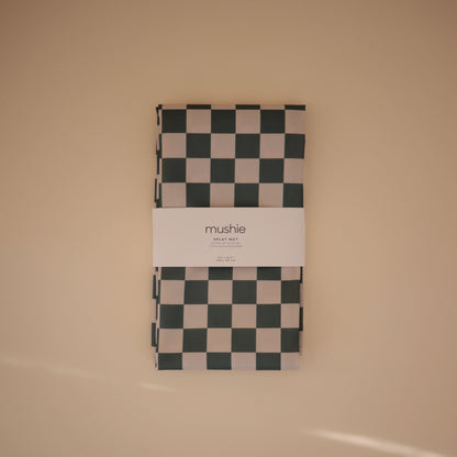 Checkered blanket with 'mushie' branding on a beige background