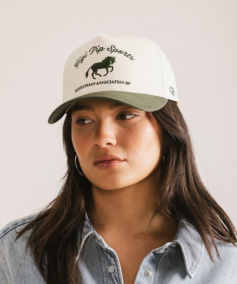 Woman wearing a white cap with green bill featuring 'High Pipp Sports' branding on a plain background