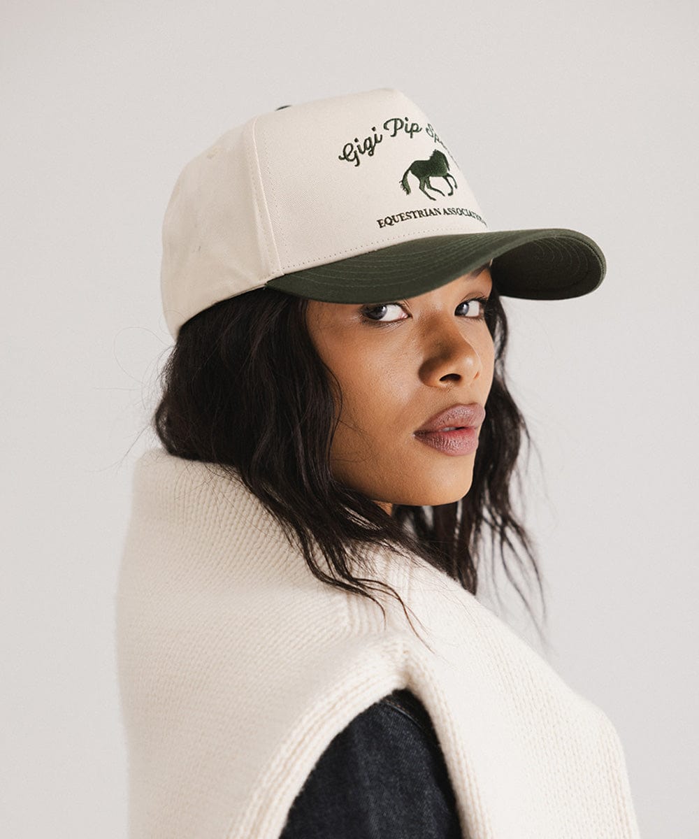 Woman wearing a beige cap with branding on a plain background