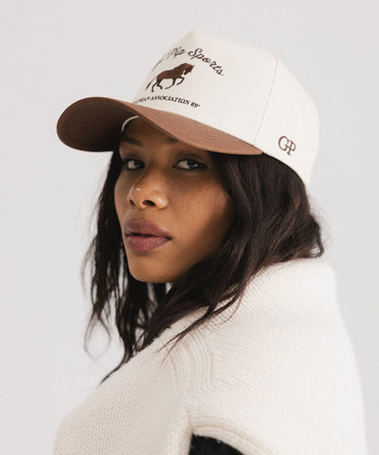 Woman wearing a cap with a logo on a plain background