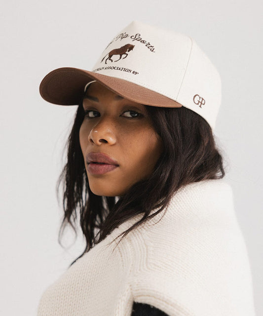Woman wearing a cap with a logo on a plain background