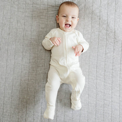 Baby in a white onesie lying on a gray textured surface