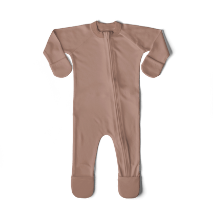 Newborn baby in a pink outfit being held by a person on a textured surface