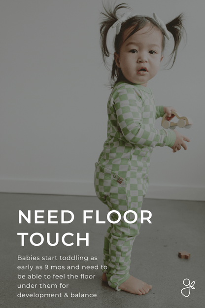 Child in a green checkered outfit standing on a gray floor with text about babies starting to toddle.
