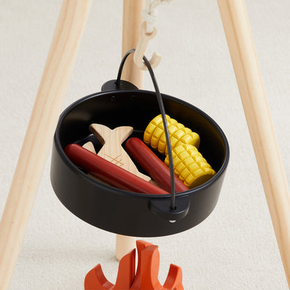 Black mini grill with toy hot dogs, corn, and wooden skewers on a white background