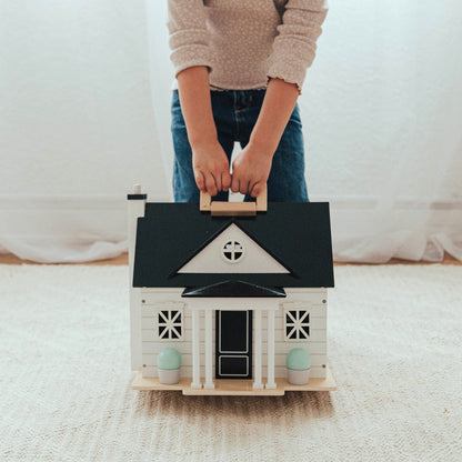 Person holding a small model house on a carpeted floor