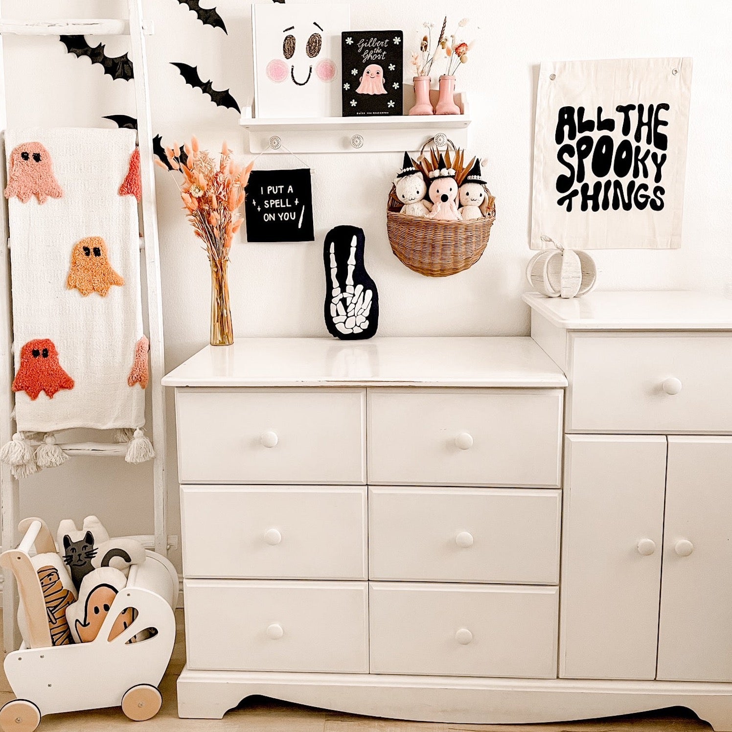 White dresser with Halloween decorations including ghosts, pumpkins, and decorative signs.