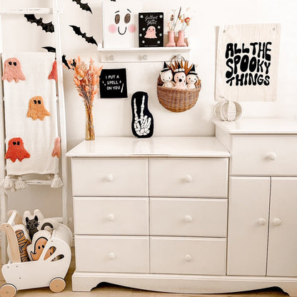 White dresser with Halloween decorations including ghosts, pumpkins, and decorative signs.