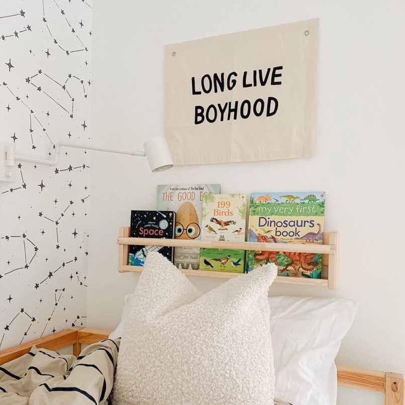 Children's bedroom with books on a shelf and a motivational sign above.