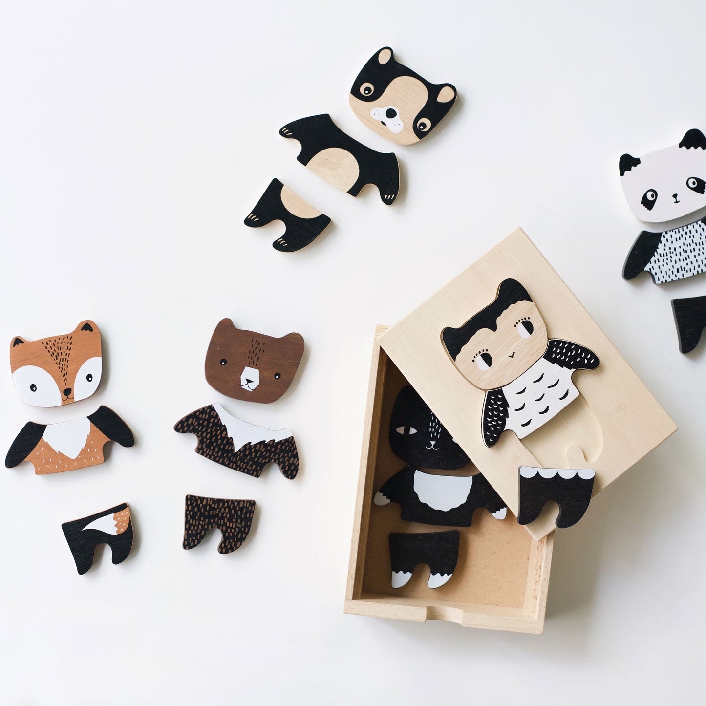 Wooden animal toys, including a panda, fox, and bear, with one toy in a box on a white background.