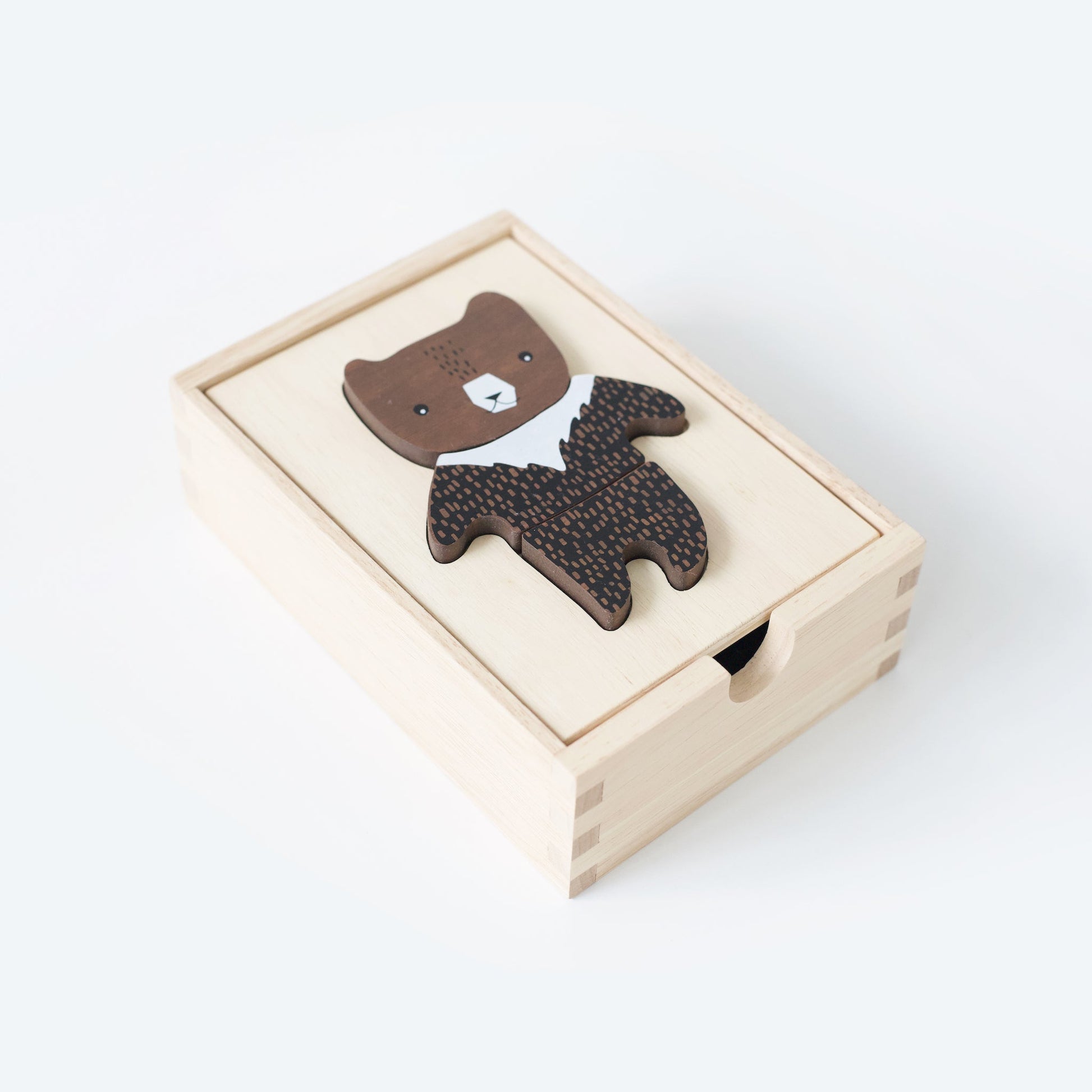 Brown bear-shaped object in a wooden box on a white background