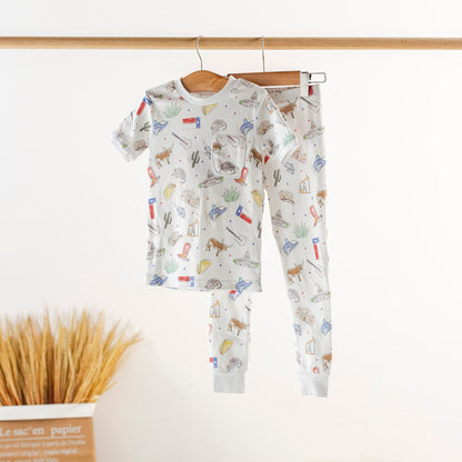 Children's pajama set with animal pattern hanging on a wooden rod.