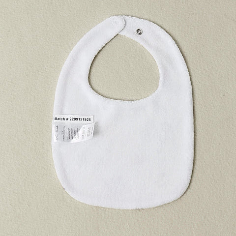 White baby bib with a label on a beige background