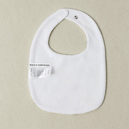 White baby bib with a label on a beige background