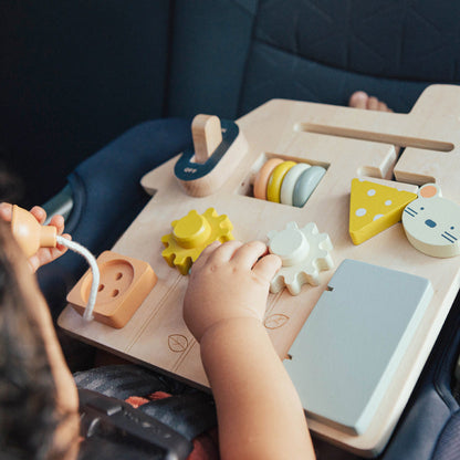 Child playing with a wooden toy set in a car seat