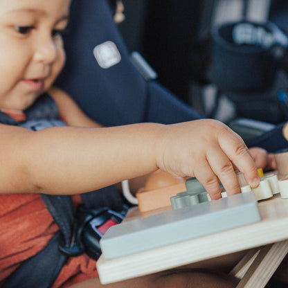 Child playing with a toy piano in a car seat