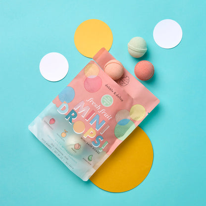 Pink packaging of 'Fresh Fruit Mini Drops' with colorful bath bombs on a blue background