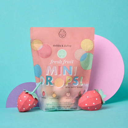 Packaging of 'fresh fruit mini drops' bath bombs with strawberry-shaped packaging on a teal background