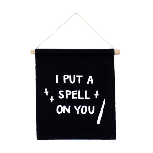 Black banner with white text 'I PUT A SPELL ON YOU' hanging on a white background