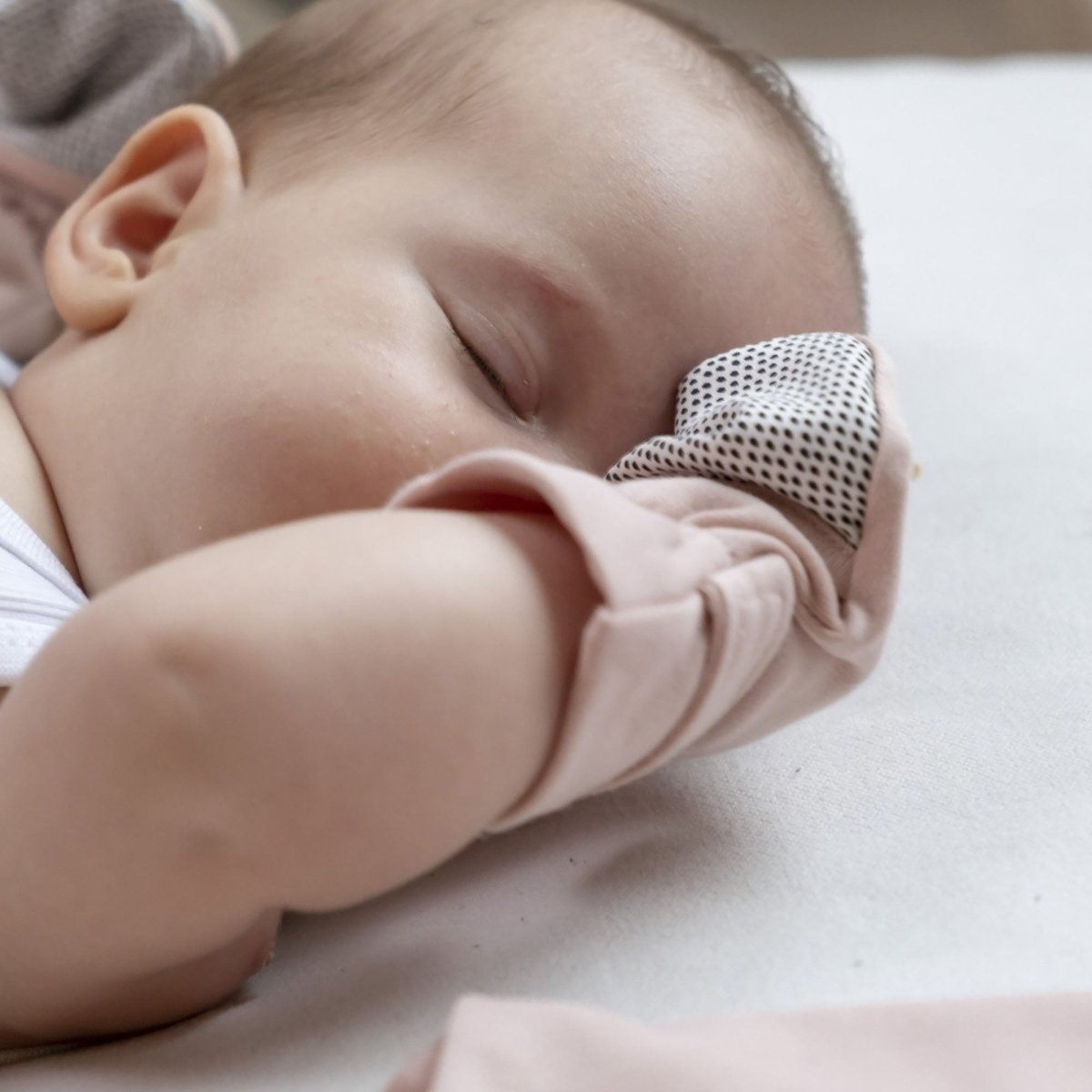 Baby wearing a polka dot headband sleeping peacefully on a soft surface