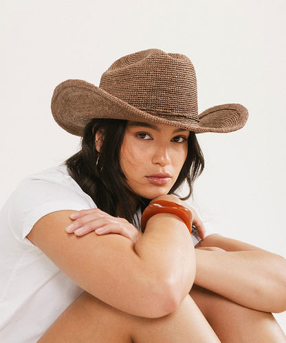 Woman wearing a brown cowboy hat on a white background