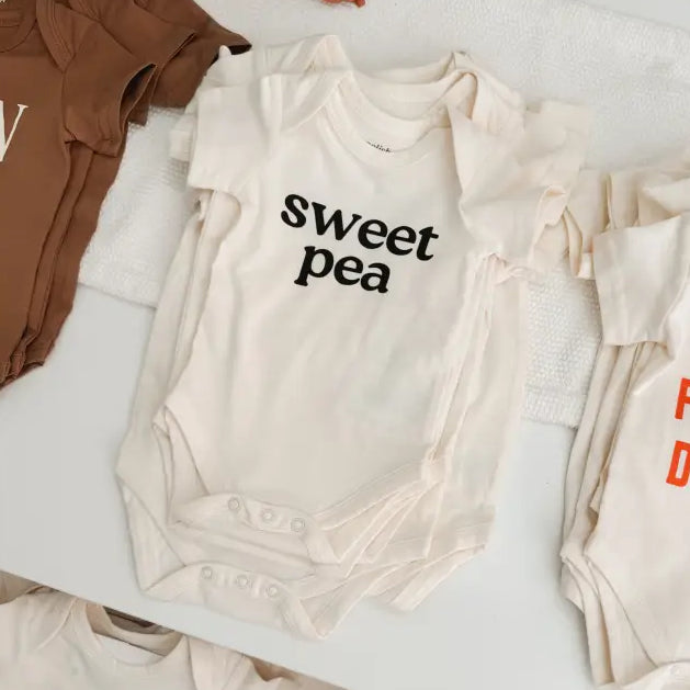 Collection of baby onesies with text on a white surface