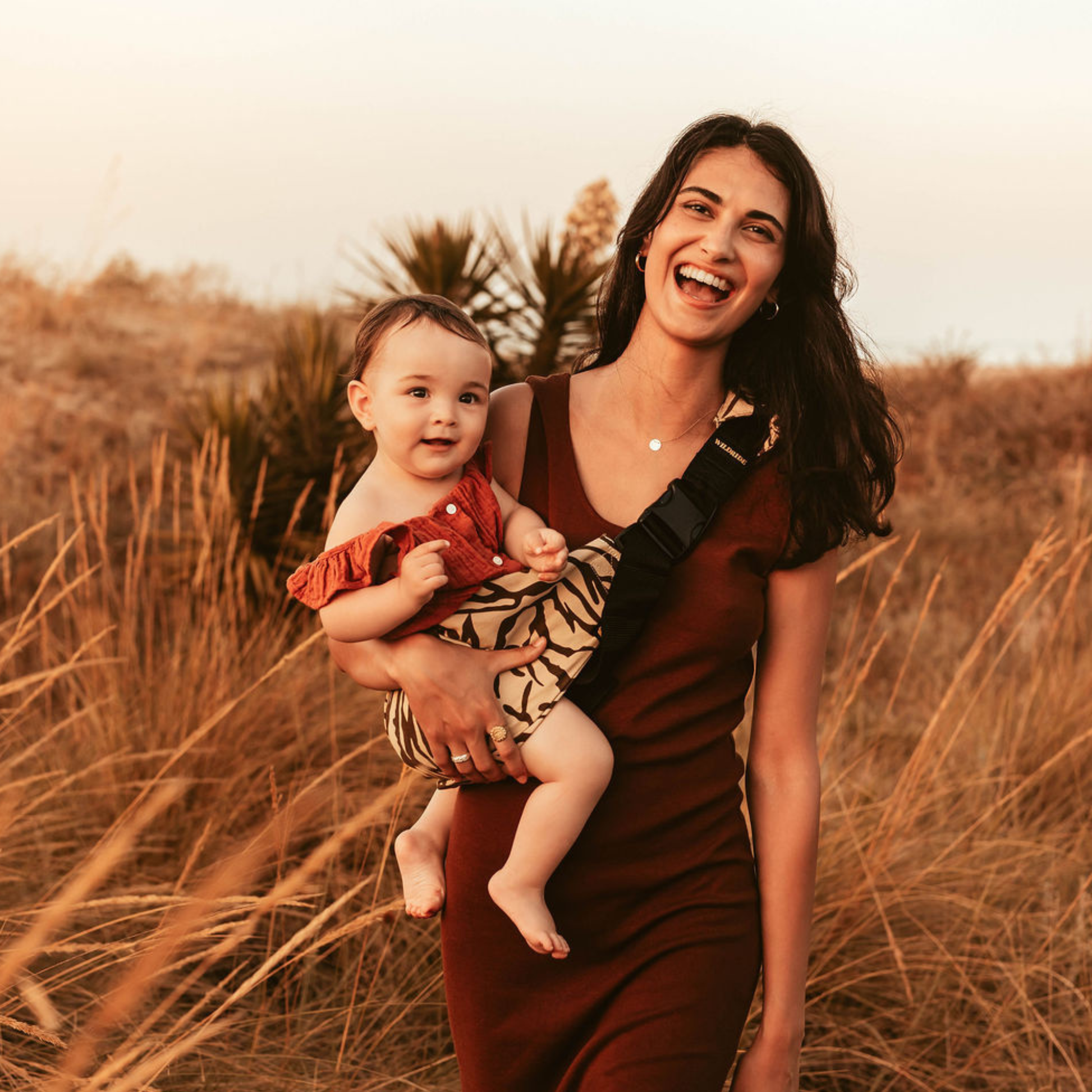 Woman holding a baby in a field with a warm, golden light